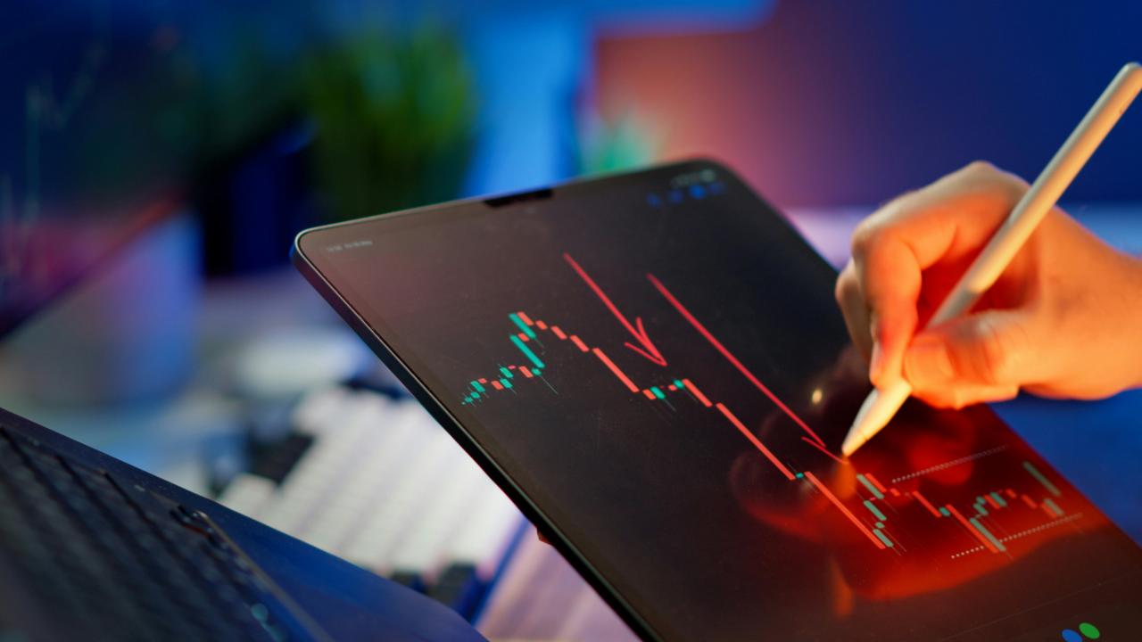 Seseorang sedang menganalisis grafik pasar saham.