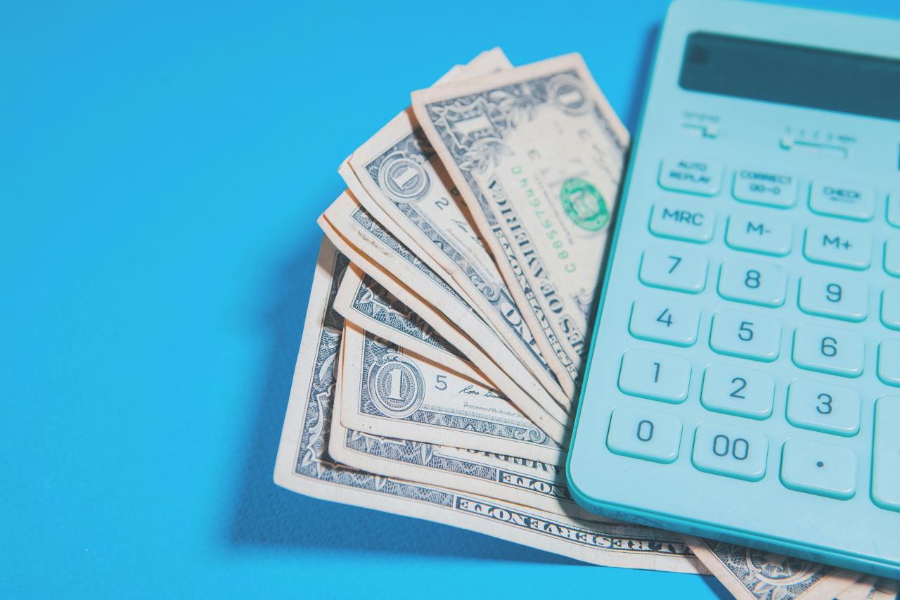 Uang dolar AS dan kalkulator dengan latar belakang biru